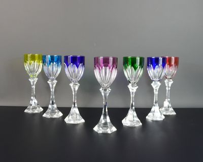 six verres à vin de couleurs différentes alignés sur une table noire