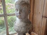 a statue of a child sitting on a table in front of a window