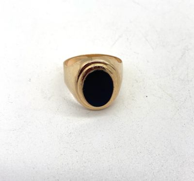 gros plan d'une bague en or avec une pierre noire