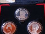 three coins in a red box with a picture of a man and a woman on them