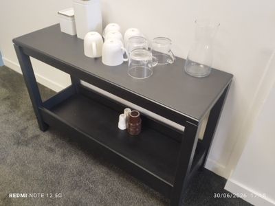 une table noire avec une étagère et des tasses posées dessus