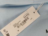 the back of a light blue hoodie with a white tag on it