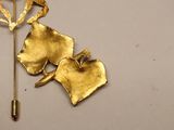 a gold brooch and a pin on a white table