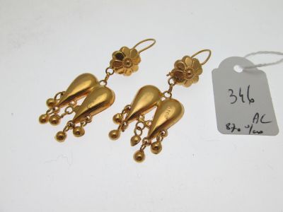 une paire de boucles d'oreilles dorées ornées de clochettes pendantes