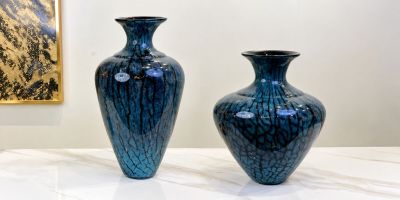 two blue vases sitting on a table in front of a painting
