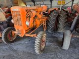a man standing next to an orange tractor in a garage