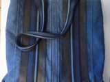 sac à main bleu et noir posé sur une surface blanche