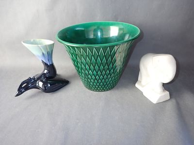two vases and a statue of a bird next to each other