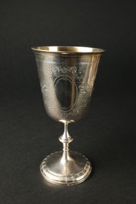 une coupe ancienne en argent posée sur un socle, sur fond noir