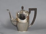 a silver tea pot with a handle on a table