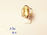 a gold ring with a leaf on it on a white surface