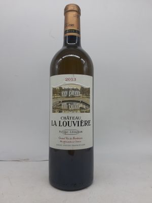 une bouteille de vin posée sur une table à côté d'un mur blanc