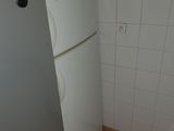 a white refrigerator in the corner of a small kitchen