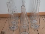 four empty glass vases sitting on a wooden floor