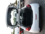 a small white car with its door open on the street