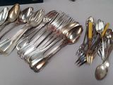 many spoons and forks laid out on a table