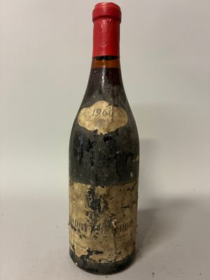 an old bottle of wine sitting on top of a white table