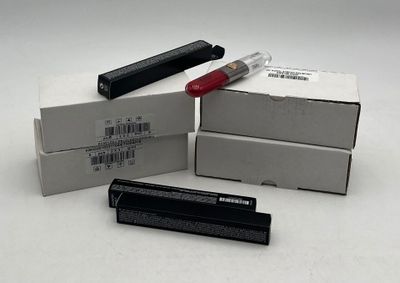 trois boîtes de rouge à lèvres et un stylo posés sur une table