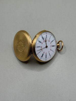 une montre de poche en or posée sur une surface blanche