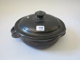un petit pot noir muni d'un couvercle posé sur une table