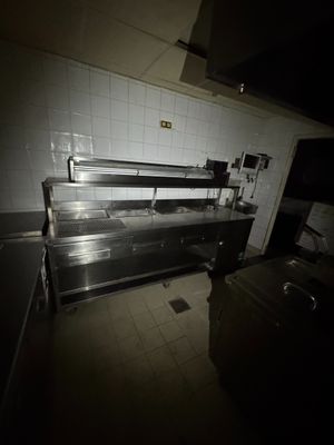coin cuisine faiblement éclairé, avec des plans de travail en acier inoxydable et des murs carrelés