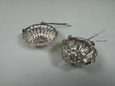 pair of silver shell shaped earrings on a white surface