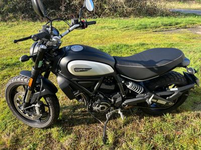 une moto noire et blanche garée dans l'herbe