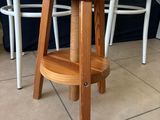 a wooden stool with a wooden seat on a tiled floor