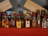 many bottles of alcohol on a table with a red table cloth
