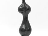 black sculpture of a female torso on a black base on a white background