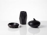 trois vases noirs posés les uns à côté des autres sur une surface blanche