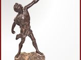 statue en bronze représentant un homme lançant un frisbee depuis le sommet d'un rocher
