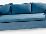un canapé bleu avec des coussins posés dessus, sur un fond blanc
