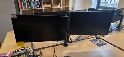 deux écrans d'ordinateur posés sur un bureau dans une pièce