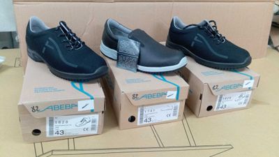 trois paires de chaussures noires sont posées sur une boîte en carton