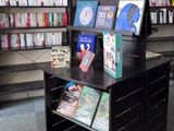 un présentoir noir sur lequel sont posés des livres, dans une bibliothèque
