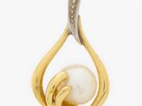 a close up of a gold and pearl pendant on a white background