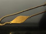 gold plated necklace with a leaf charm on a black surface