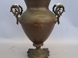 a bronze vase with two handles on a stand