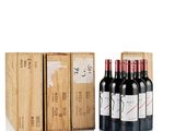 three bottles of red wine in a wooden box next to a stack of boxes