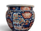 un vase bleu et orange muni d'un couvercle, posé sur une surface blanche