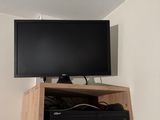 a flat screen tv mounted on the wall above a shelf