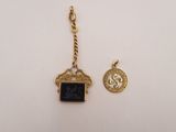 a gold charm with a black stone and a coin on it