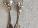 deux cuillères en argent et une fourchette posées sur une nappe blanche