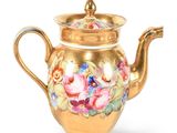 gold plated teapot with flowers and leaves on it on a white background