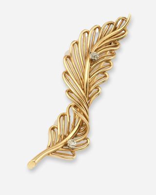 un gros plan sur une broche en feuille d'or sertie d'un diamant
