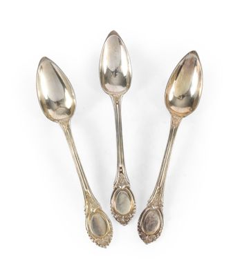 trois cuillères en argent et une cuillère avec un manche, posées sur une surface blanche