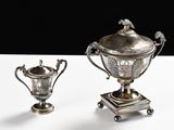 two silver vases sitting on top of a table next to each other