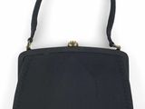 le petit sac à main noir est posé sur une surface blanche