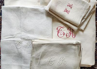 plusieurs serviettes blanches ornées de monogrammes brodés, posées sur un tapis
